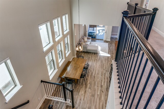 stairway featuring baseboards, a high ceiling, and wood finished floors