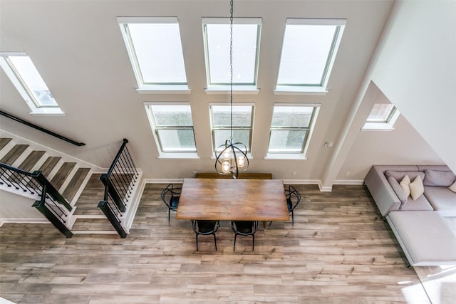 dining room with stairway, a towering ceiling, baseboards, and wood finished floors