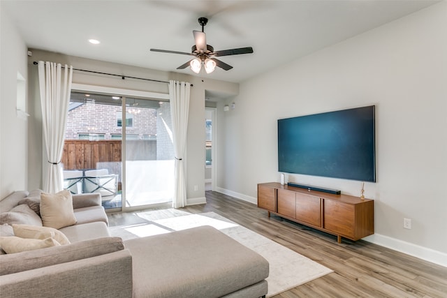 living room with ceiling fan, baseboards, and wood finished floors