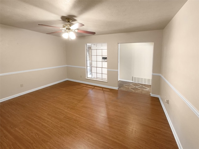 unfurnished room with a textured ceiling, dark hardwood / wood-style flooring, and ceiling fan