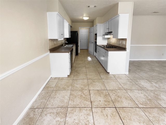 kitchen with tasteful backsplash, sink, white cabinetry, appliances with stainless steel finishes, and light tile patterned floors