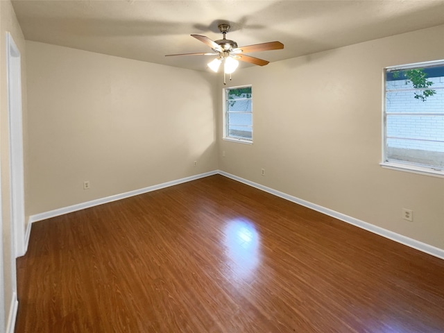 empty room featuring a wealth of natural light, ceiling fan, and dark hardwood / wood-style flooring