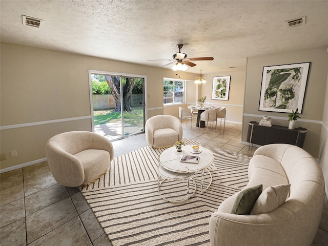 living room with ceiling fan, a textured ceiling, and light tile patterned flooring