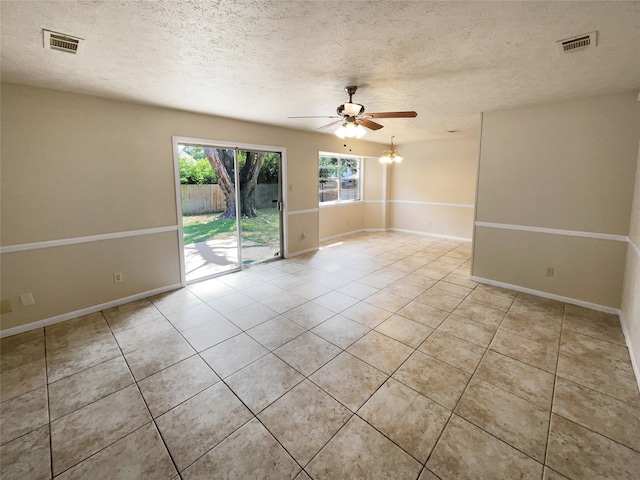 tiled empty room with ceiling fan and a textured ceiling