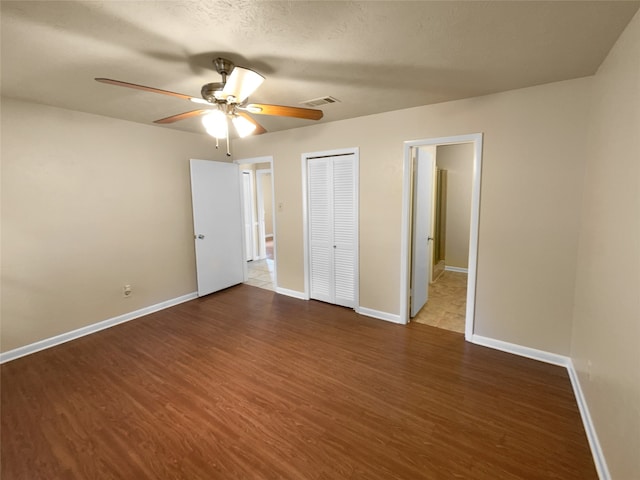 unfurnished bedroom featuring a textured ceiling, ceiling fan, and dark wood-type flooring