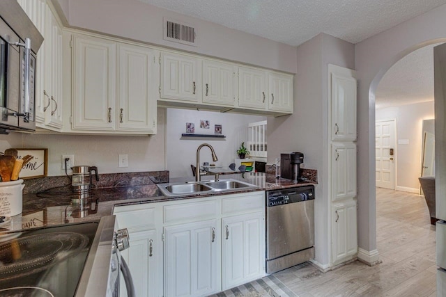 kitchen with light hardwood / wood-style floors, a textured ceiling, sink, white cabinets, and appliances with stainless steel finishes