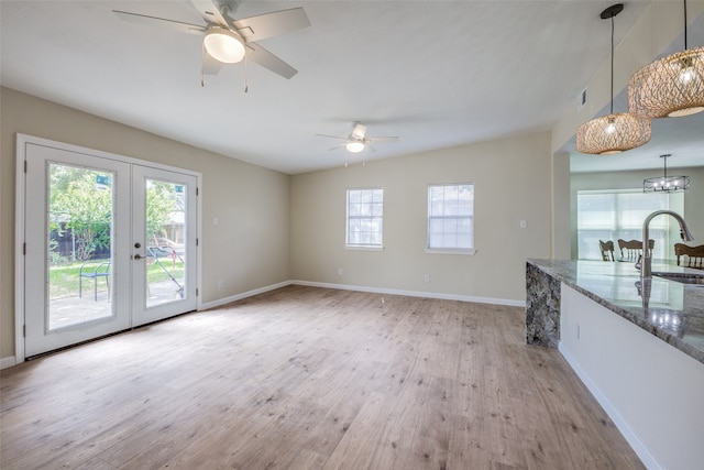 interior space featuring ceiling fan with notable chandelier, light hardwood / wood-style floors, sink, and french doors