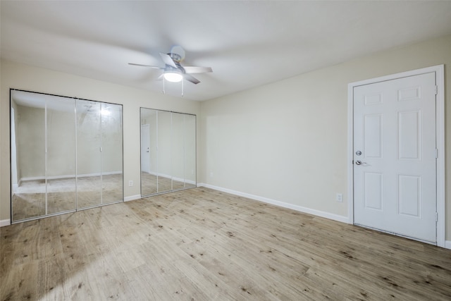 unfurnished bedroom with two closets, light hardwood / wood-style flooring, and ceiling fan