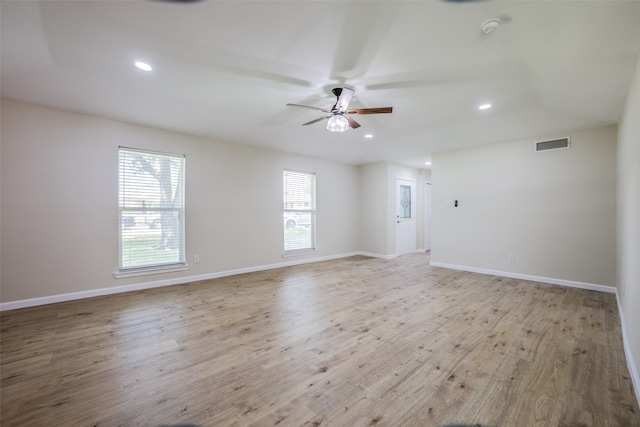 spare room with a tray ceiling, ceiling fan, and light hardwood / wood-style floors