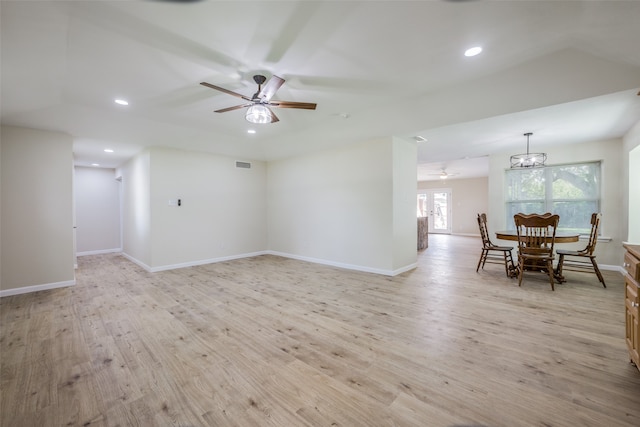 spare room with ceiling fan with notable chandelier and light hardwood / wood-style floors