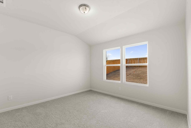 carpeted empty room with lofted ceiling