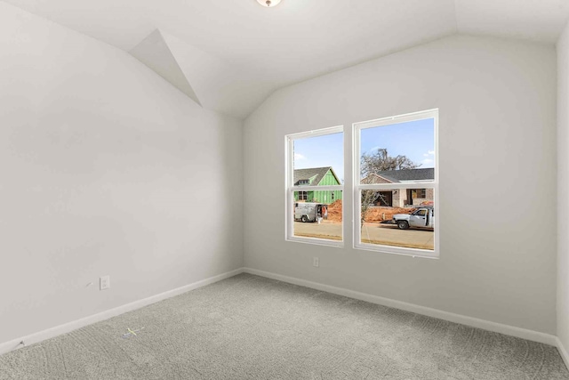 carpeted spare room featuring lofted ceiling