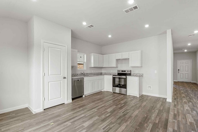 kitchen with appliances with stainless steel finishes, white cabinetry, sink, light stone counters, and light hardwood / wood-style flooring