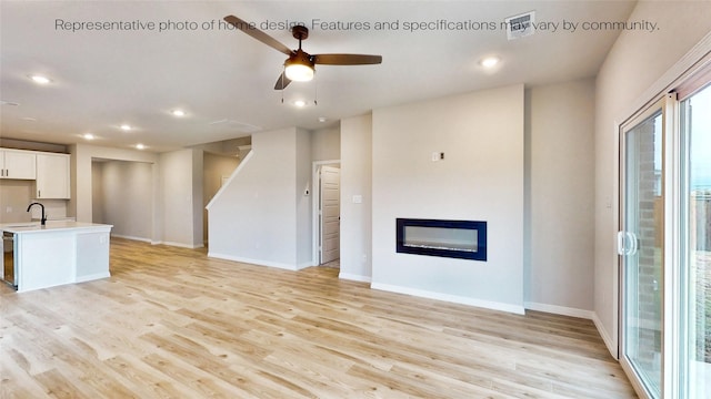 unfurnished living room featuring ceiling fan, sink, and light hardwood / wood-style flooring