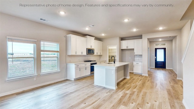 kitchen with white cabinets, stainless steel appliances, a kitchen island with sink, and sink