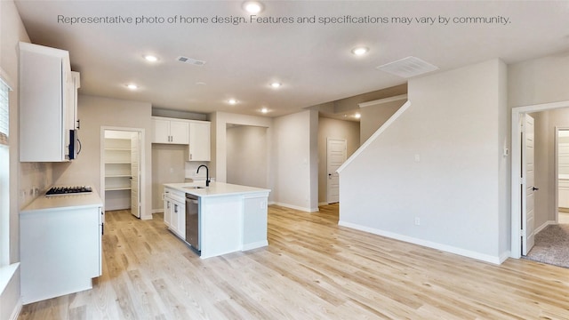 kitchen with white cabinetry, dishwasher, gas stovetop, light hardwood / wood-style floors, and a kitchen island with sink