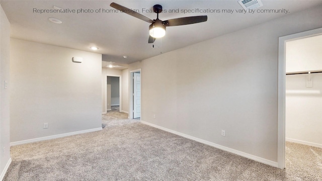 unfurnished bedroom featuring light carpet, a walk in closet, a closet, and ceiling fan