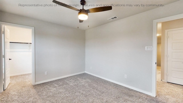 unfurnished bedroom with a closet, a walk in closet, light colored carpet, and ceiling fan