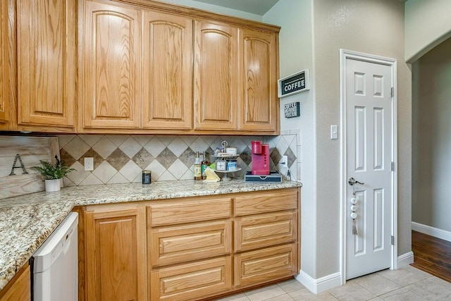 kitchen with light stone counters, white dishwasher, backsplash, and light tile patterned flooring