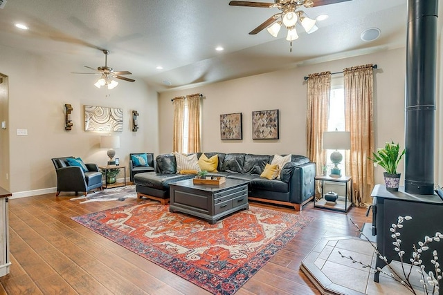 living room featuring ceiling fan, dark hardwood / wood-style floors, vaulted ceiling, and a wood stove