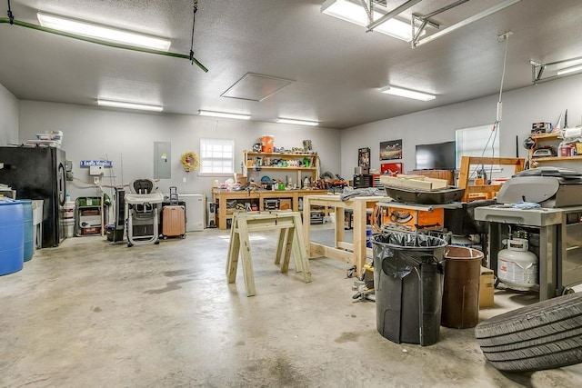 garage with black fridge, electric panel, and a workshop area