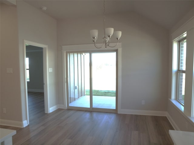 unfurnished dining area featuring a chandelier, vaulted ceiling, and hardwood / wood-style floors