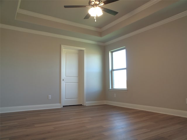 spare room featuring ceiling fan, a tray ceiling, dark hardwood / wood-style floors, and crown molding