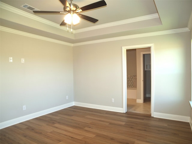 unfurnished room with a tray ceiling, ornamental molding, dark hardwood / wood-style flooring, and ceiling fan