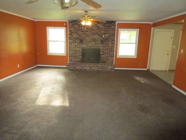 unfurnished living room with ceiling fan, carpet, a brick fireplace, and crown molding