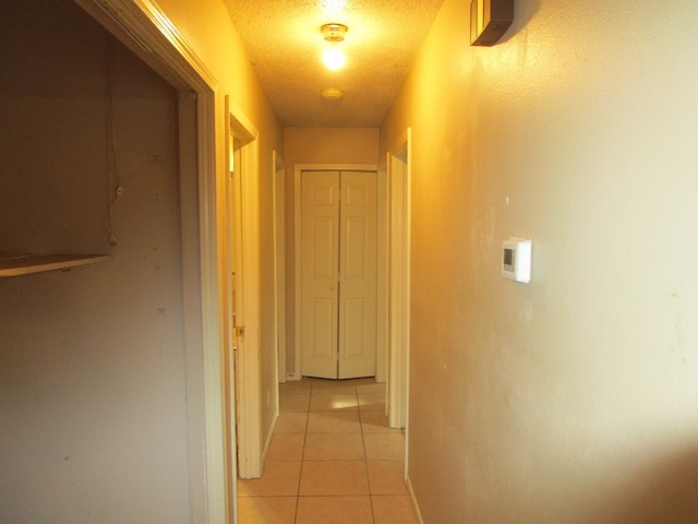 hall with a textured ceiling and light tile patterned flooring