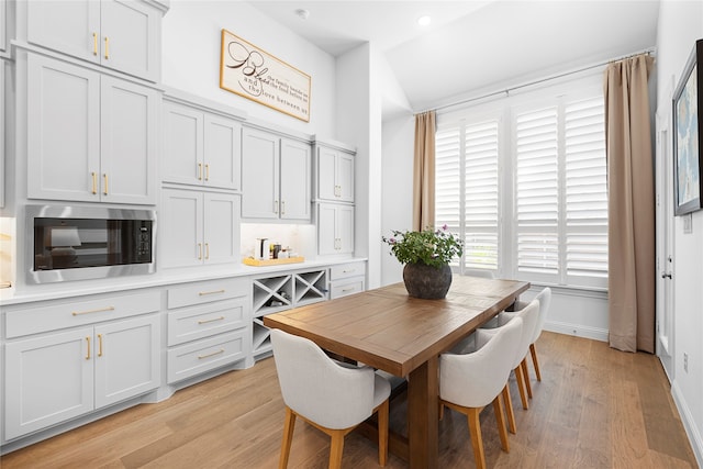 dining area featuring light wood-type flooring and vaulted ceiling