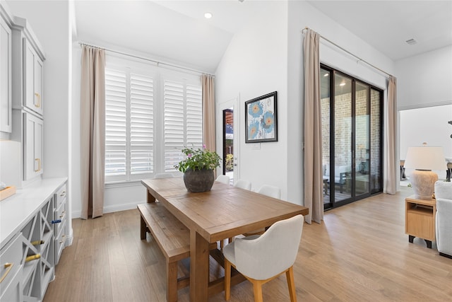 dining room featuring light wood-type flooring, vaulted ceiling, and plenty of natural light