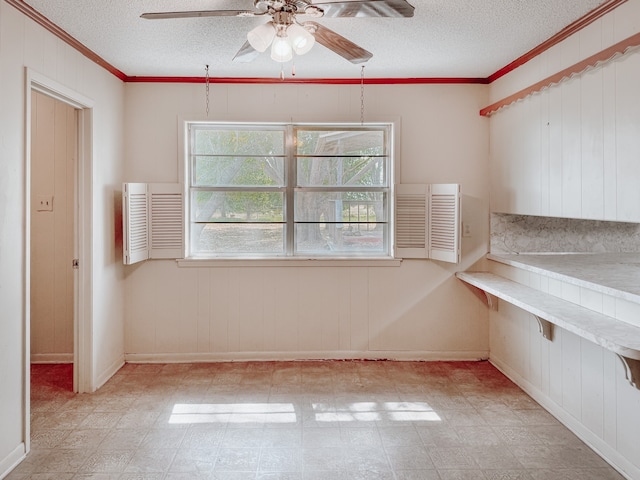 unfurnished dining area with a textured ceiling, ceiling fan, and crown molding