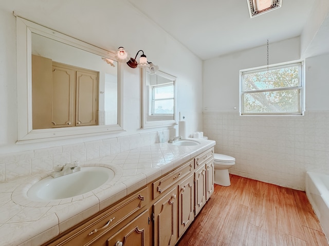 bathroom featuring vanity, a bathtub, toilet, tile walls, and hardwood / wood-style floors