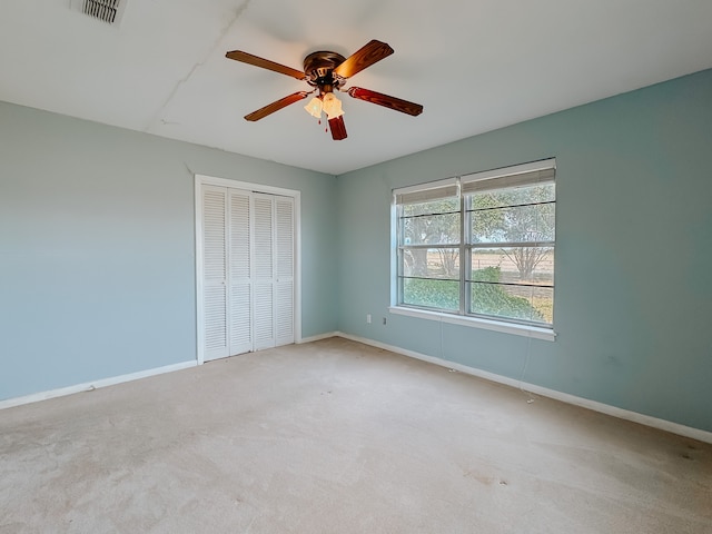 unfurnished bedroom featuring light carpet, a closet, and ceiling fan