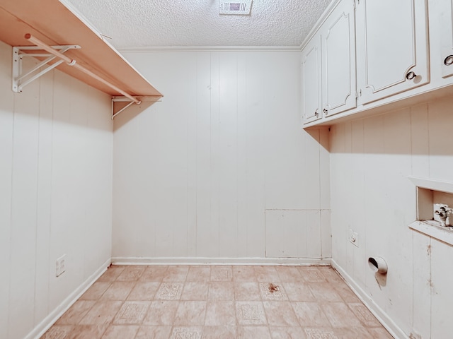 clothes washing area featuring cabinets, wooden walls, a textured ceiling, and washer hookup