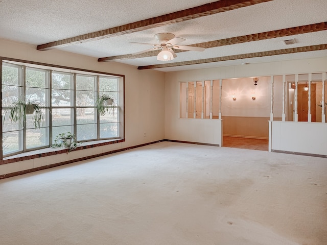 carpeted empty room featuring ceiling fan, beamed ceiling, and a textured ceiling