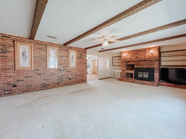 unfurnished living room featuring a brick fireplace, carpet floors, brick wall, beamed ceiling, and ceiling fan