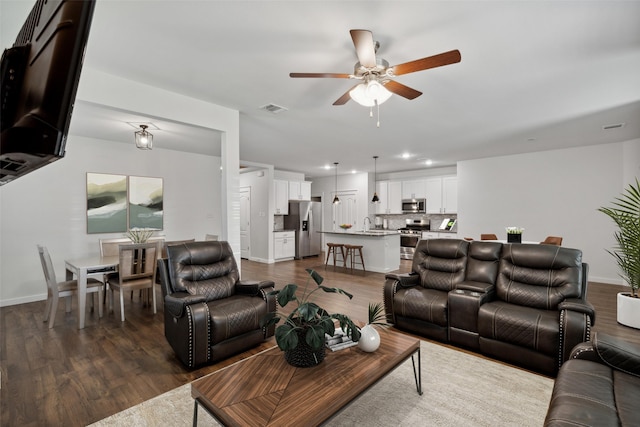 living room with ceiling fan and dark wood-type flooring