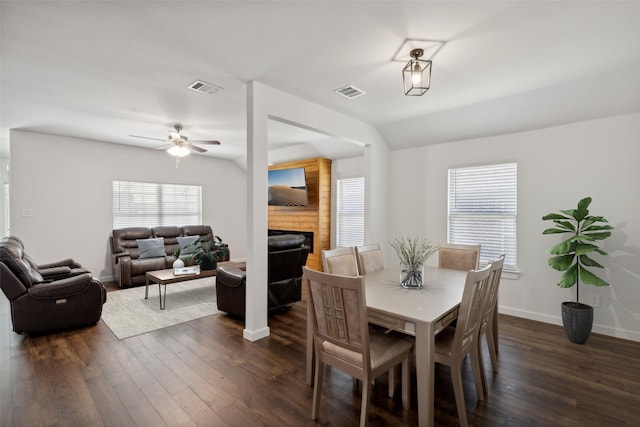 dining space featuring a fireplace, ceiling fan, and dark wood-type flooring