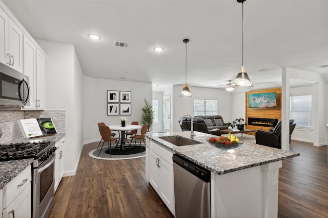 kitchen featuring sink, white cabinetry, stainless steel appliances, and a kitchen island with sink