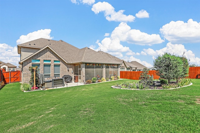 rear view of property featuring a lawn, a sunroom, and a patio area