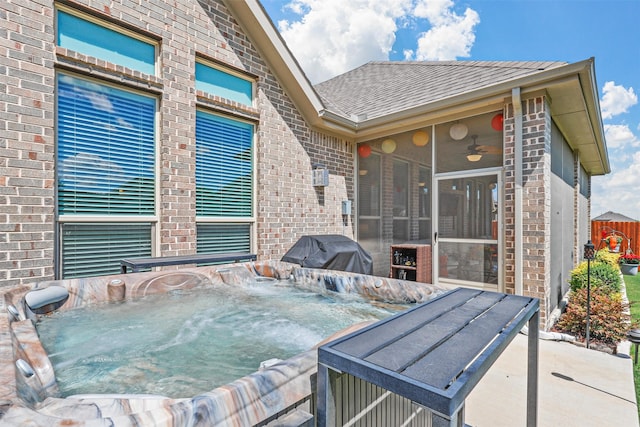 view of patio featuring a sunroom, a grill, and a hot tub