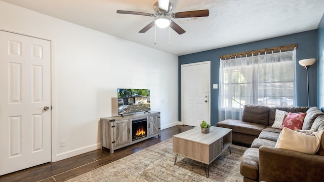 living room featuring ceiling fan, a fireplace, and dark hardwood / wood-style flooring