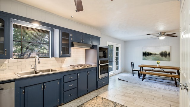 kitchen with sink, backsplash, appliances with stainless steel finishes, blue cabinets, and ceiling fan