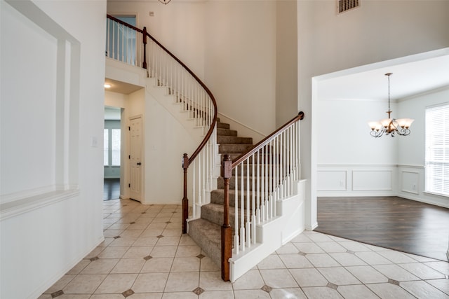 entryway with light wood-type flooring, a towering ceiling, and a chandelier