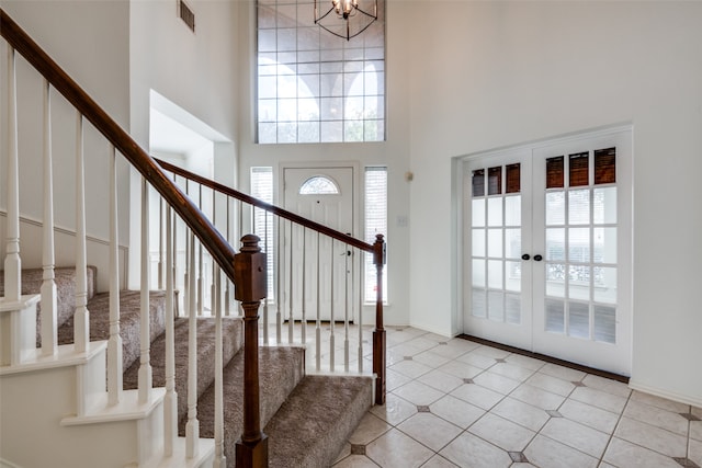 entrance foyer featuring a towering ceiling, french doors, a chandelier, and light tile patterned floors