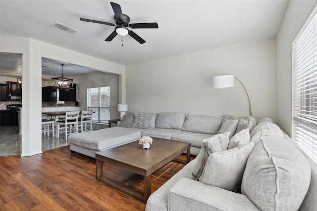 living room featuring ceiling fan with notable chandelier and dark hardwood / wood-style flooring