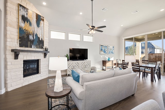 living room with ceiling fan, lofted ceiling, a stone fireplace, and dark hardwood / wood-style flooring