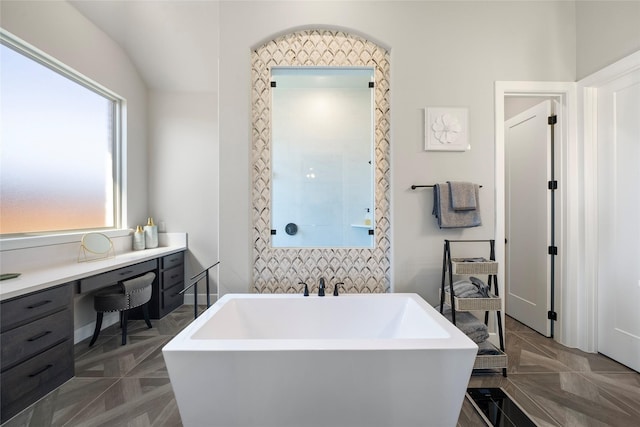 bathroom with parquet flooring, lofted ceiling, and a washtub